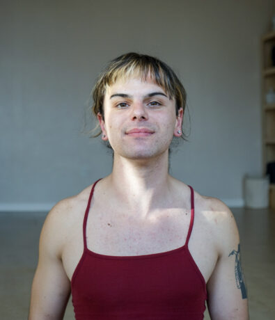 Headshot of Corey. He has short hair with bangs, and wearing a red tank top.