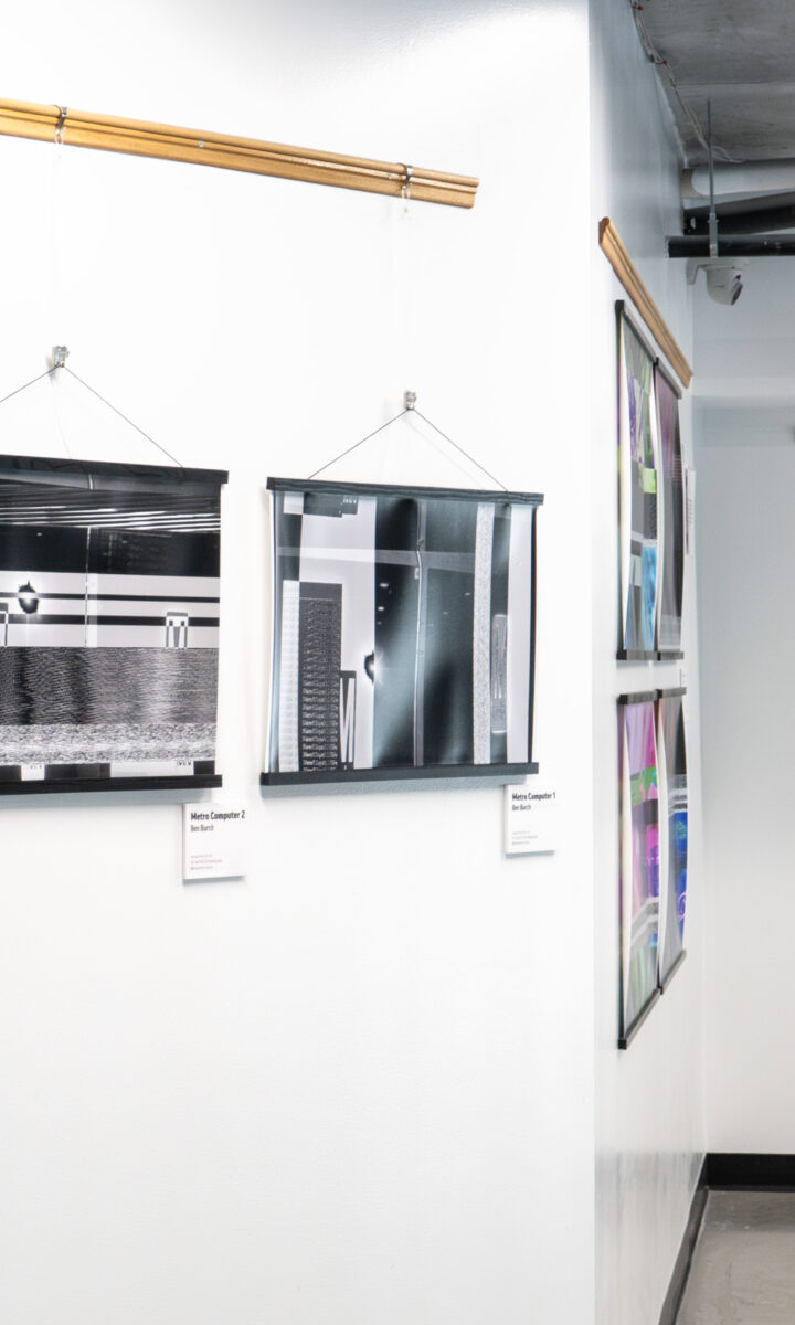 Four abstract black and white photographs hang on white gallery walls at a DC arts space, each with a label beneath. A hallway leads to more framed artwork, with pipes and an exposed ceiling visible above. Part of the Community Arts Program.