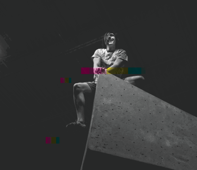 A person sits triumphantly atop a large indoor climbing wall at Boulderfest, smiling and gripping the edge. The image is mostly black and white with several digital color glitches across the scene.